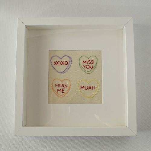 Broderie de cœurs en bonbons encadrée dans un cadre photo carré