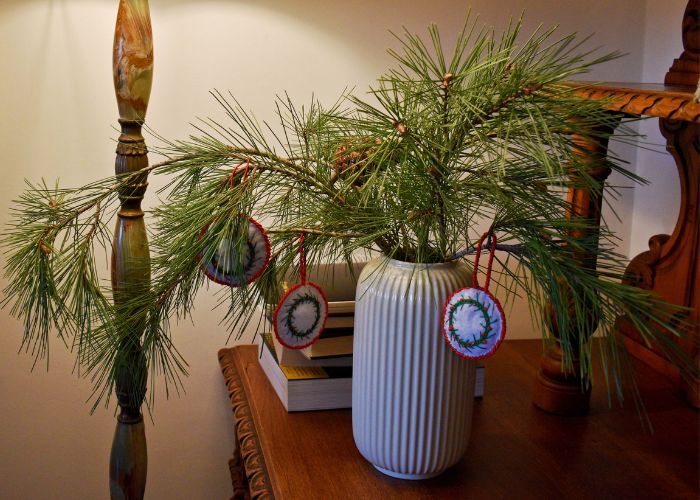 Branche de pin dans un vase décoré d'ornements faits à la main