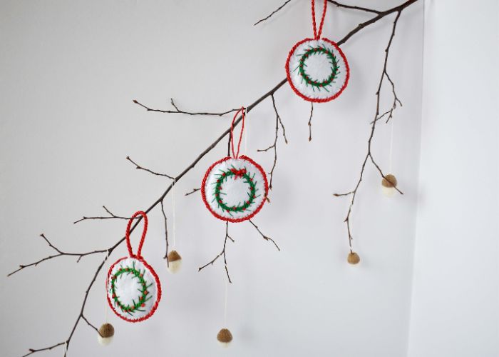 Branche d'arbre décorée avec des ornements DIY et des glands